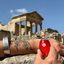 Katari Rubi rosehip oil held in front of an ancient Roman temple in Tunisia