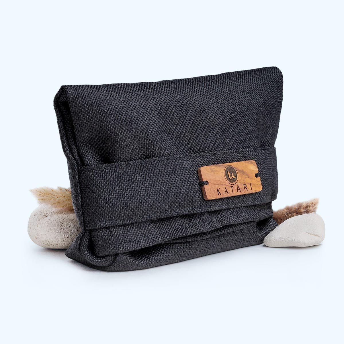 black linen makeup bag with an olive wood decorative button with Katari logo on a light background