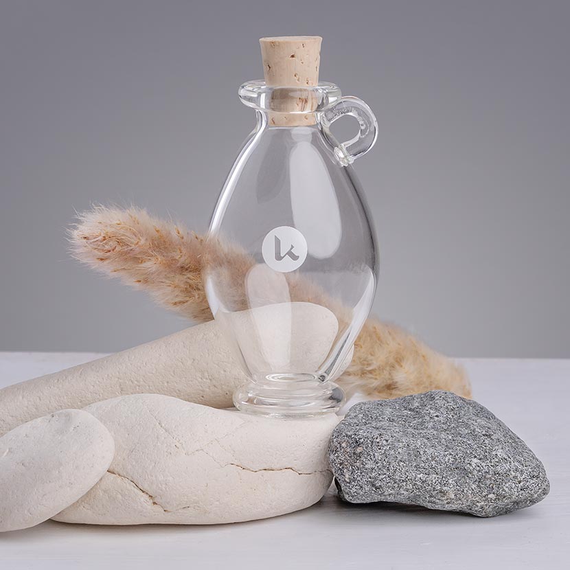 Clear hand blown glass bottle with cork stopper on a gray background - 1 fl oz