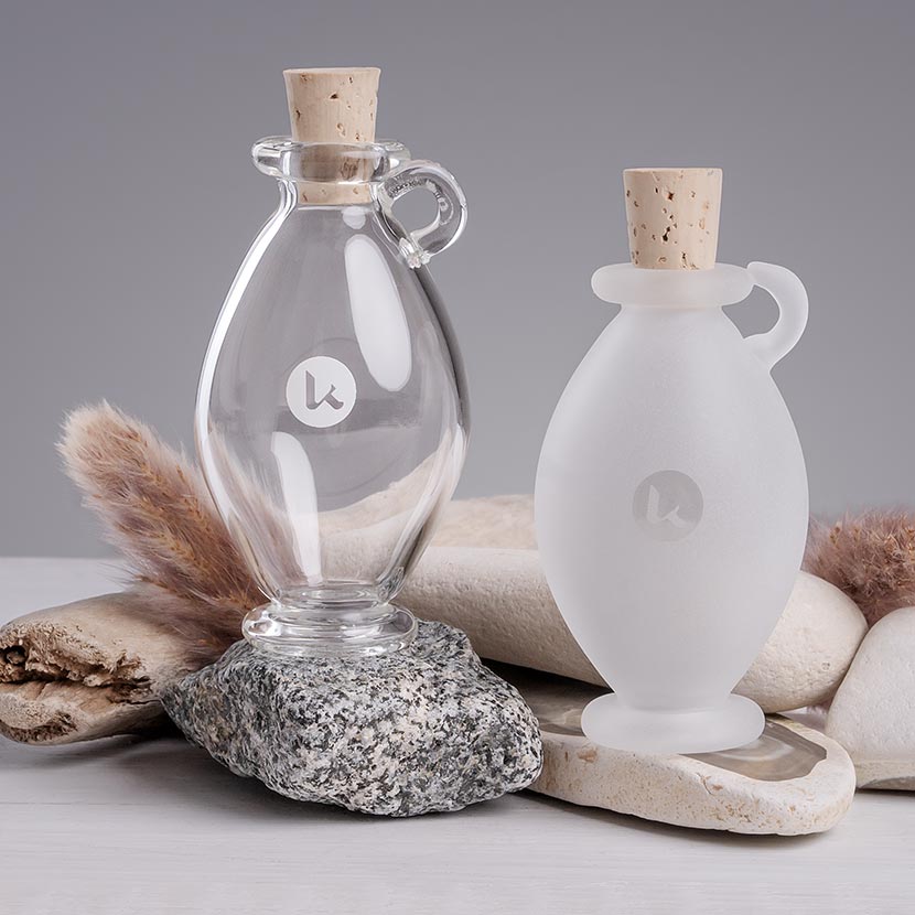 Two hand blown glass bottles with cork stoppers on a neutral background - 1 fl oz