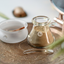Green clay in a hand-blown glass jar with the frosted mixing bowl and glass spoon on an engraved brass tray