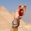 Hand holding Katari black seed oil in a hand-blown glass amphora at the pyramids of Giza