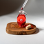 Dropper of Katari Granate pomegranate seed oil over a hand-blown glass amphora on an olivewood board