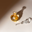 Open bottle of Katari Nuit Sicilienne perfume oil with its glass stopper beside it in sunlight