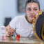 Woman applying Katari Granate Oil, a 100% pure cold-pressed pomegranate seed oil, from a small hand-blown glass amphora during her skincare routine.