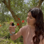 Kate misting Katari Roseau rose water under an olive tree with red poppies
