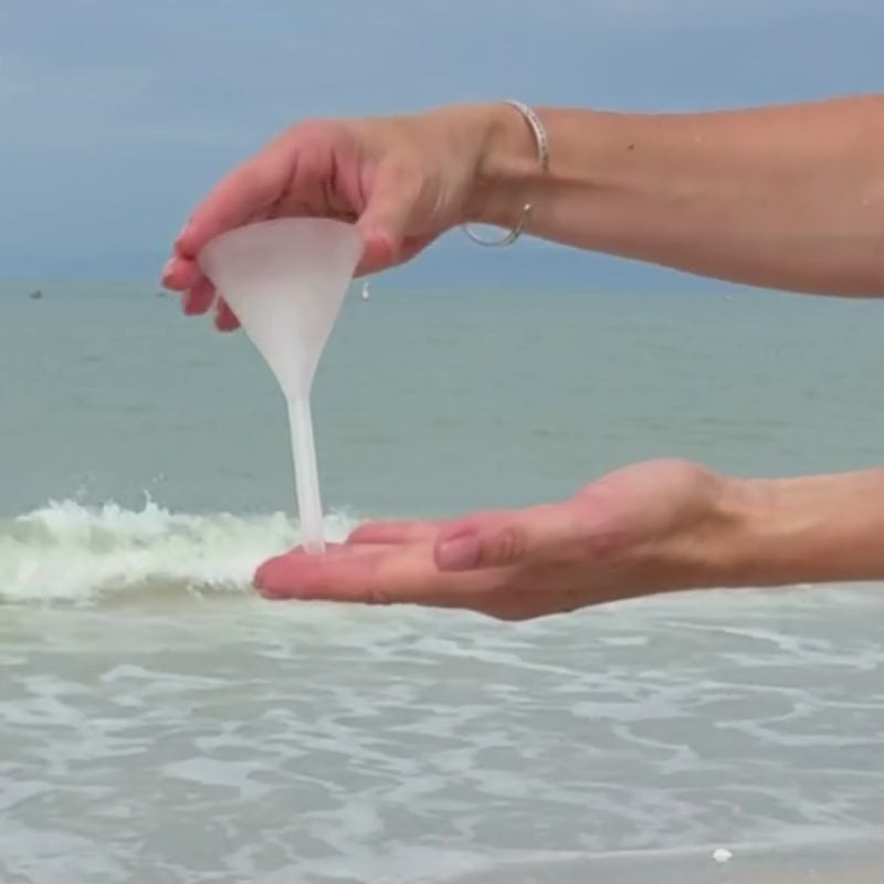 video of a frosted glass funnel being held in front of the ocean background