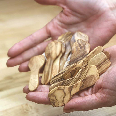 Hand-carved olive wood spatulas in the hands